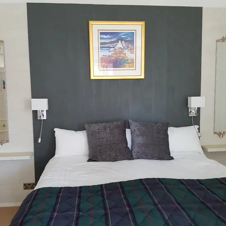 a bedroom with a bed with a picture on the wall at Kilmichael House in Drumnadrochit