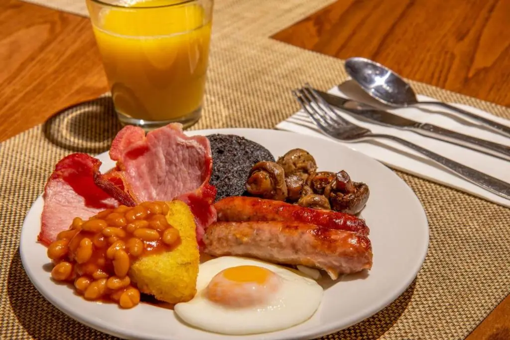 a plate of breakfast food with eggs bacon beans and meat at Coylumbridge Resort Hotel in Aviemore