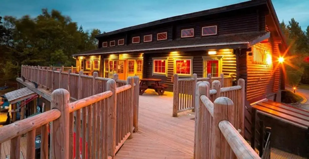 a wooden cabin with a wooden walkway to a building at Coylumbridge Resort Hotel in Aviemore