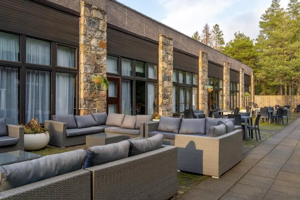 a patio with couches and tables in front of a building at Coylumbridge Resort Hotel in Aviemore