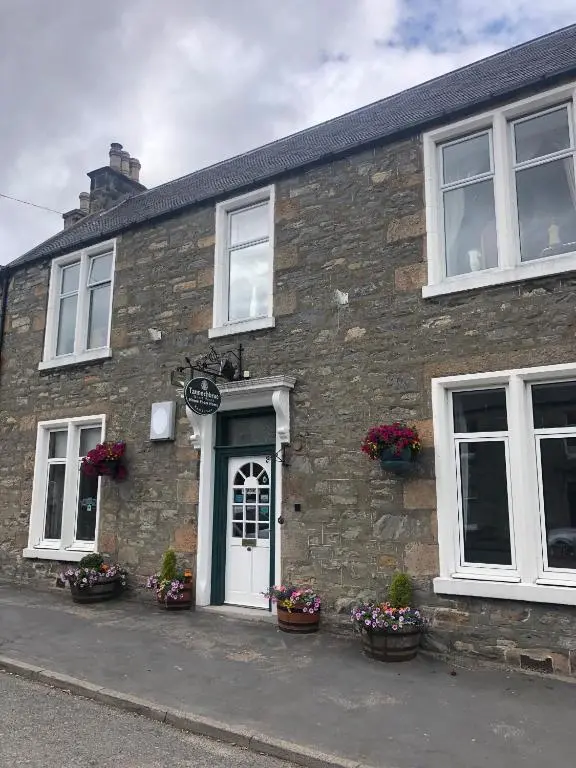 a stone building with white windows and a door at The Tannochbrae in Dufftown