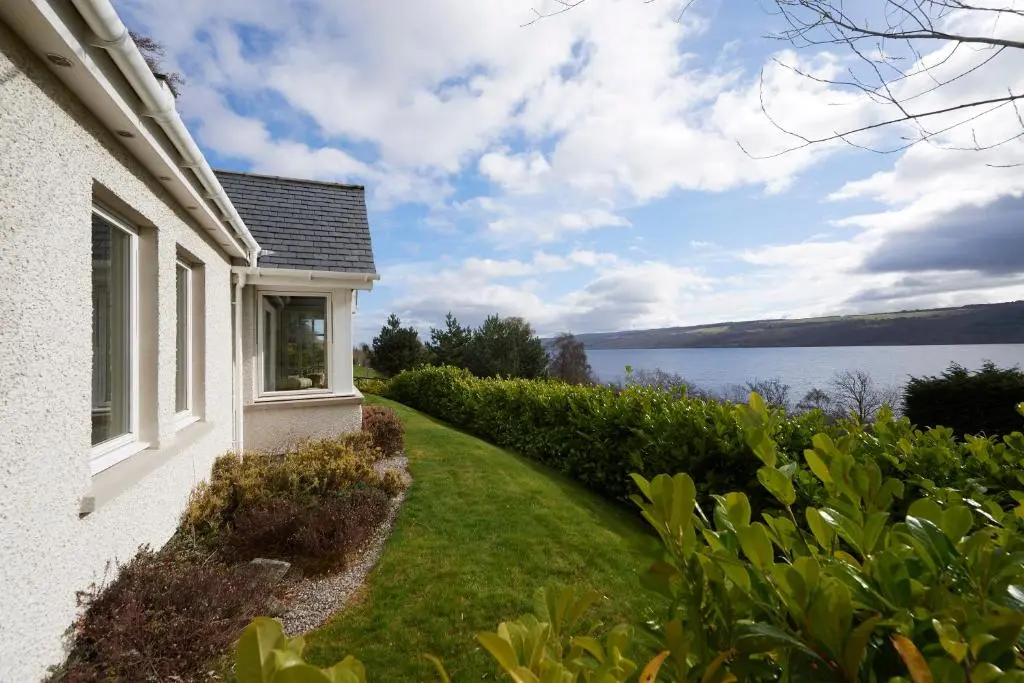 a white house with a view of the water at Loch Ness Cottages in Brackla