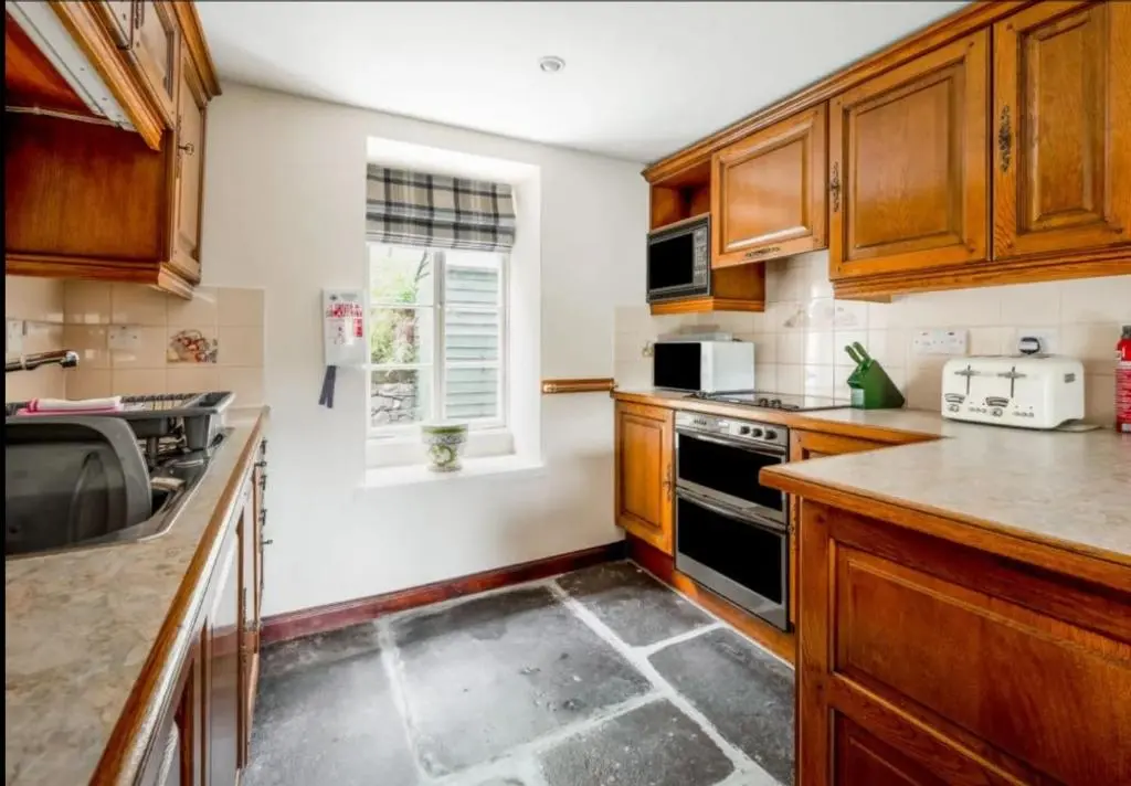 a kitchen with wooden cabinets and a stove top oven at Loch Ness Cottages in Brackla