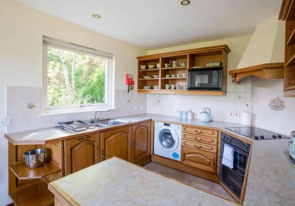 a kitchen with a sink and a washing machine at Loch Ness Cottages in Brackla