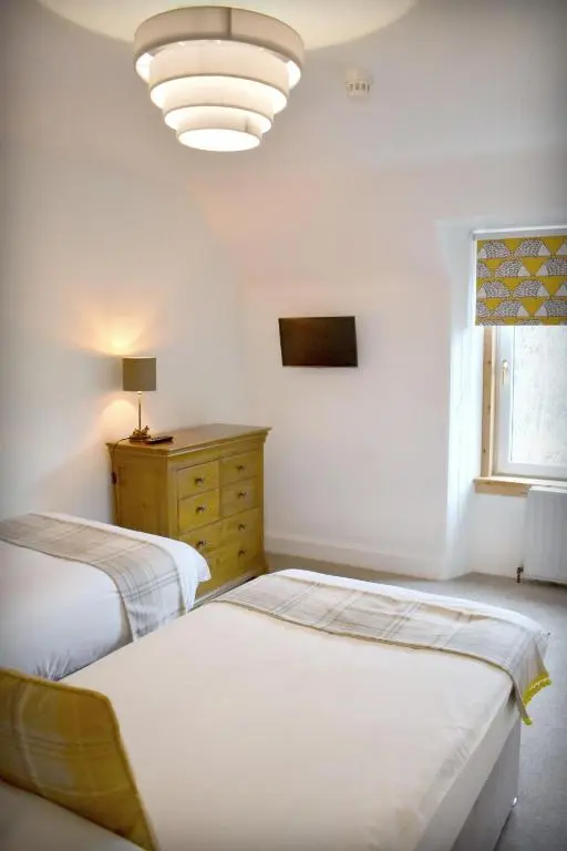 two beds in a room with a lamp and a dresser at The \u2018Servants Quarters@Delny House\u2019 in Invergordon