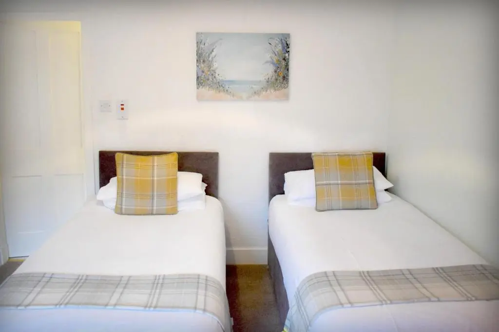 two beds in a room with white walls at The \u2018Servants Quarters@Delny House\u2019 in Invergordon