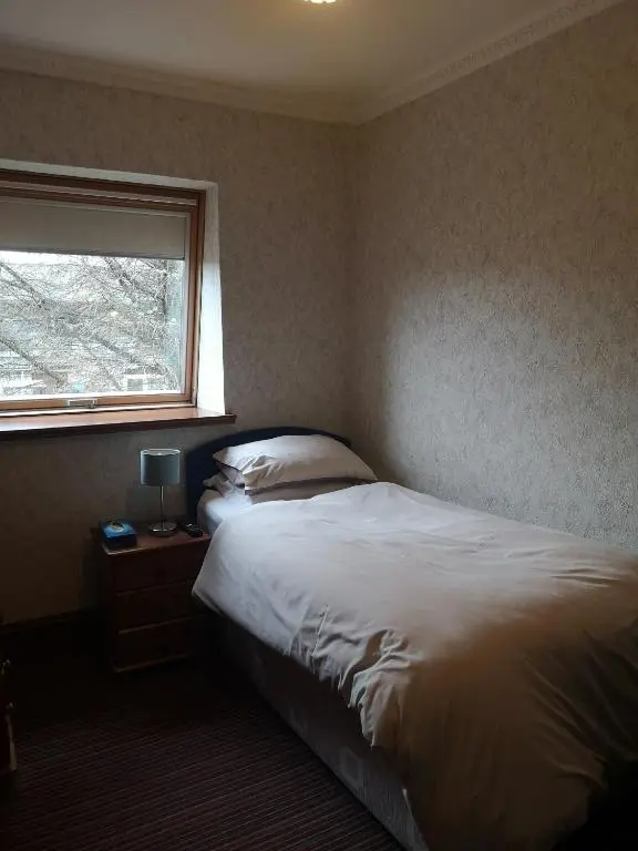 a bedroom with a white bed and a window at Granville Guest House in Dyce
