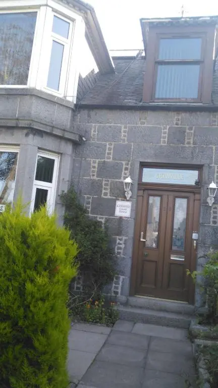 a brick house with a wooden door in front at Granville Guest House in Dyce