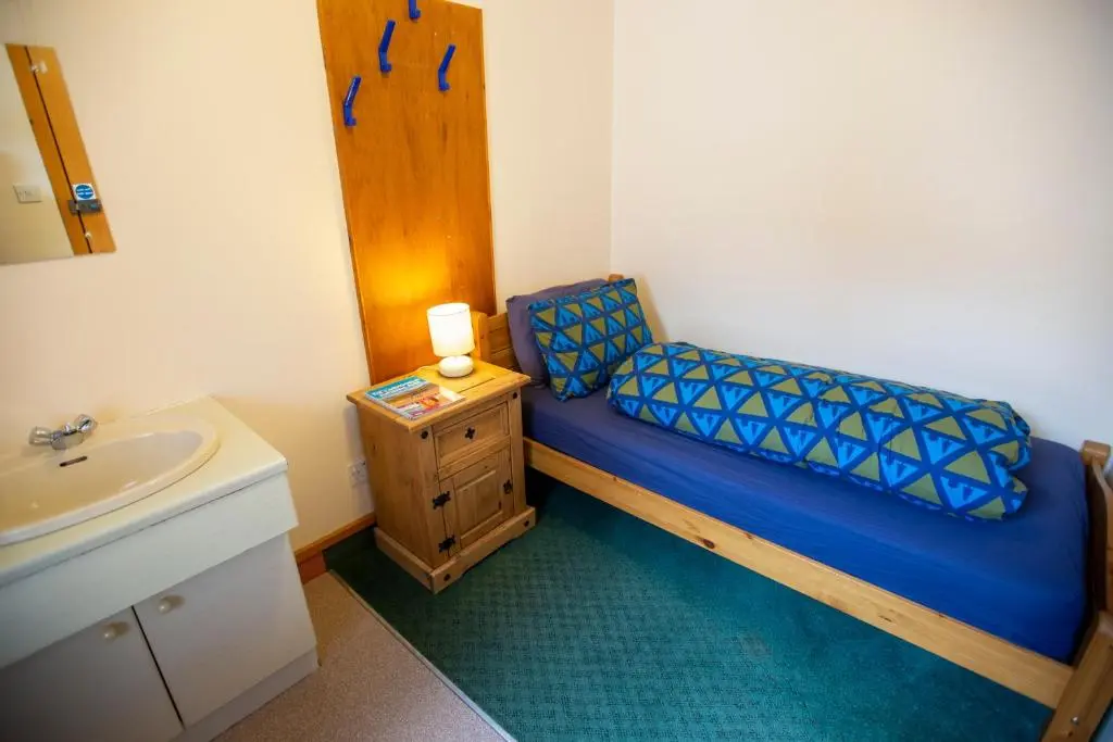 a small bedroom with a blue bed and a sink at Aviemore Youth Hostel in Aviemore