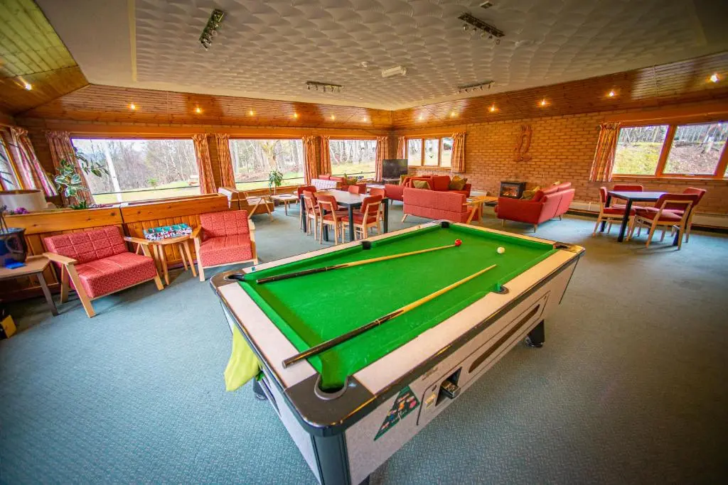 a pool table in a room with tables and chairs at Aviemore Youth Hostel in Aviemore
