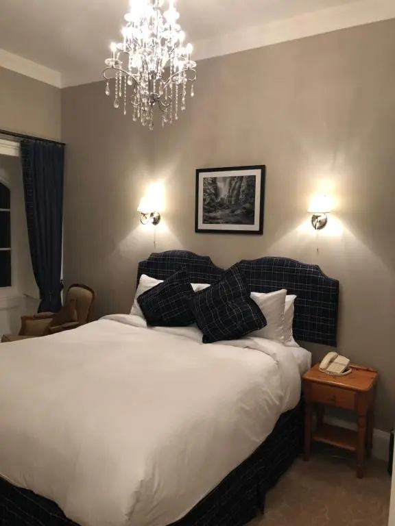 a bedroom with a large bed and a chandelier at Coul House Hotel in Contin