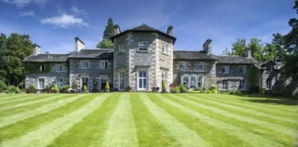 a large stone house with a large grass field at Coul House Hotel in Contin