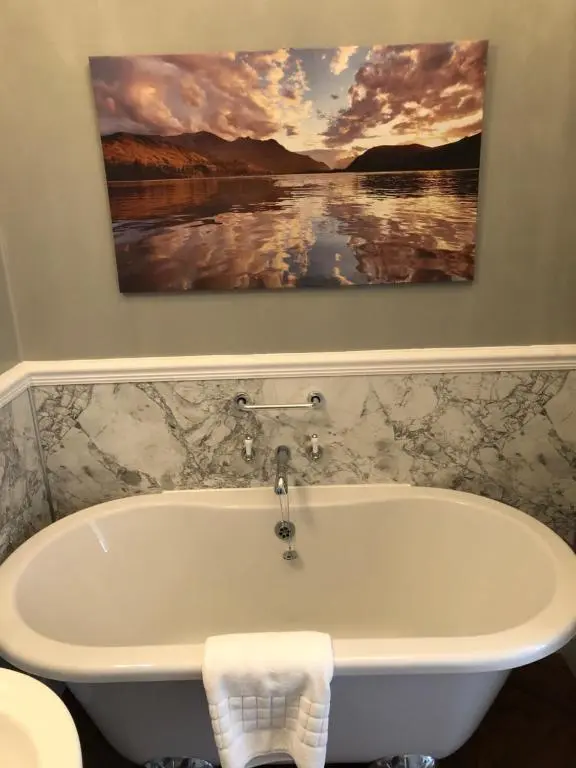 a bath tub in a bathroom with a painting on the wall at Coul House Hotel in Contin