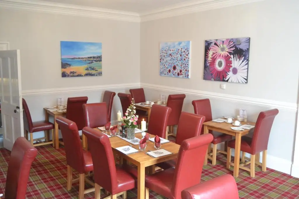 a dining room with tables and chairs and paintings at Southbank Guesthouse in Elgin