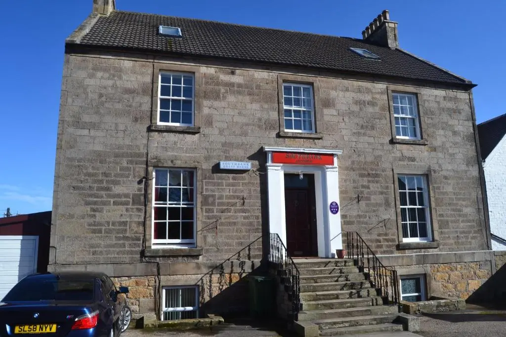 an old brick building with a car parked in front at Southbank Guesthouse in Elgin