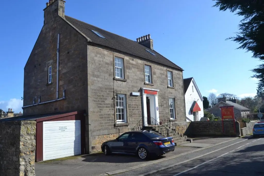 a car parked in front of a brick building at Southbank Guesthouse in Elgin