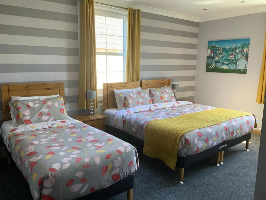 two beds in a room with striped walls at Southbank Guesthouse in Elgin