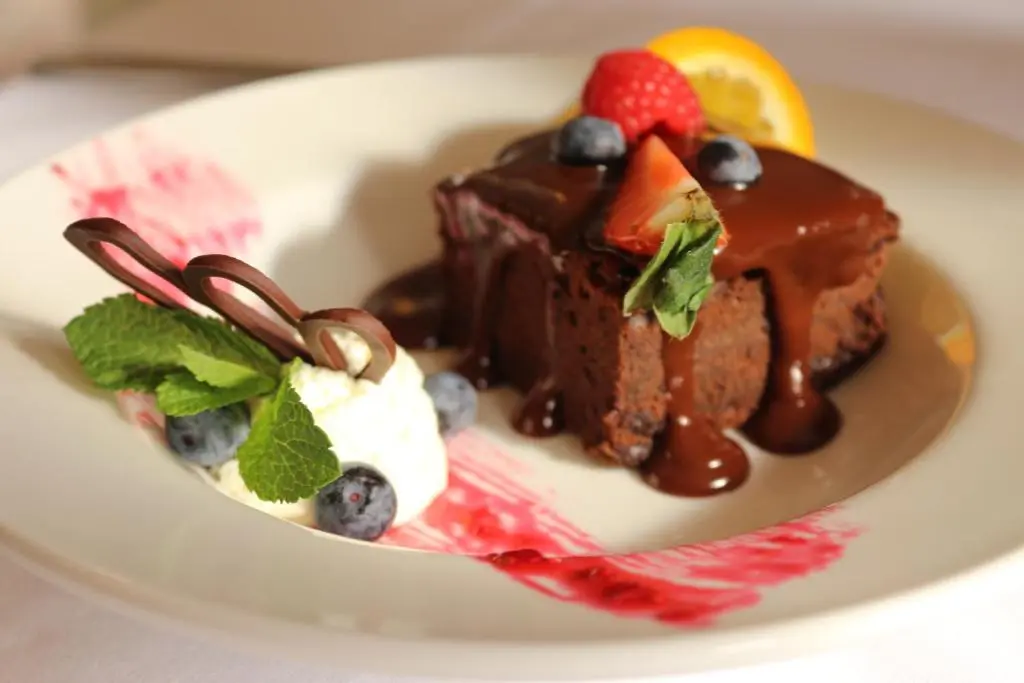 a piece of chocolate cake with fruit on a plate at Craiglynne Hotel in Grantown on Spey