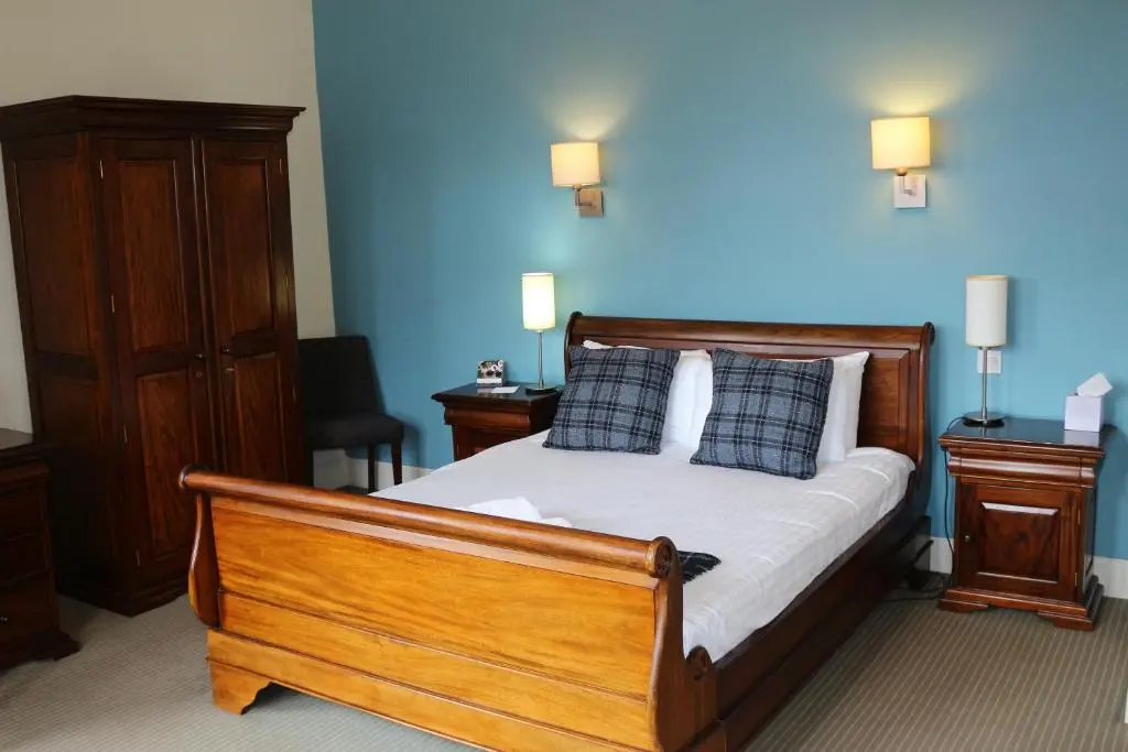 a bedroom with a wooden bed with blue walls at Craiglynne Hotel in Grantown on Spey