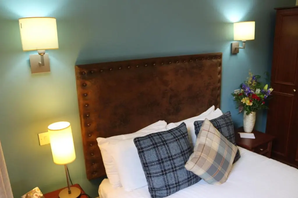 a bedroom with a bed with two lamps and two pillows at Craiglynne Hotel in Grantown on Spey