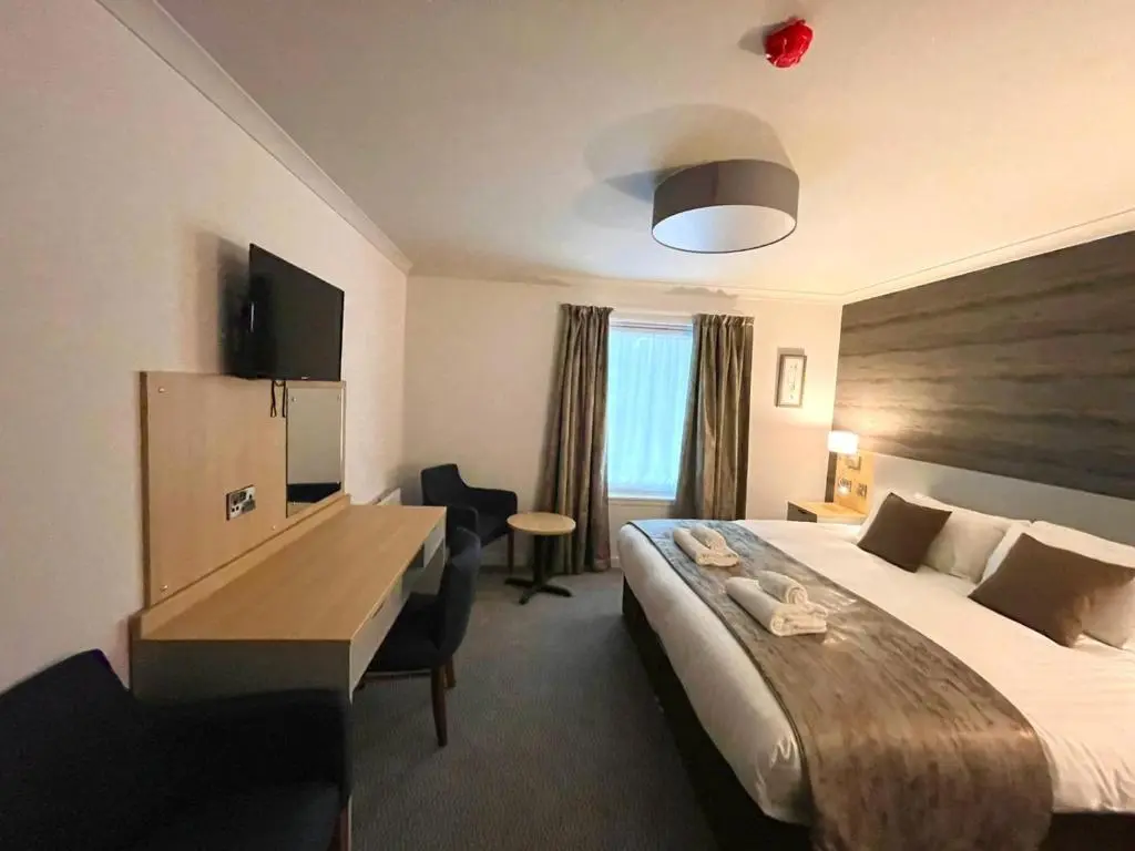 a hotel room with a large bed and a desk at Craiglynne Hotel in Grantown on Spey