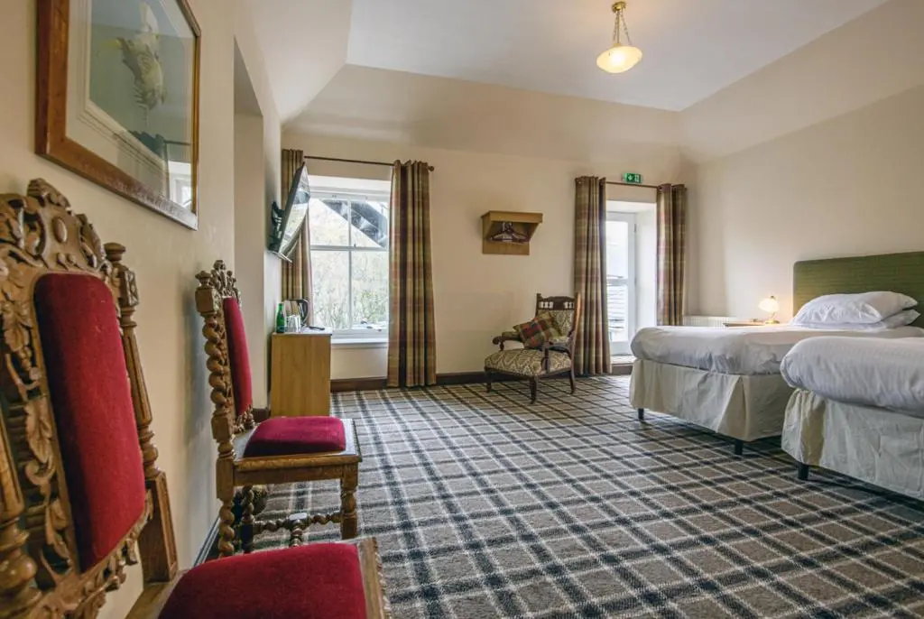 a hotel room with two beds and a chair at The Bridge Helmsdale in Helmsdale
