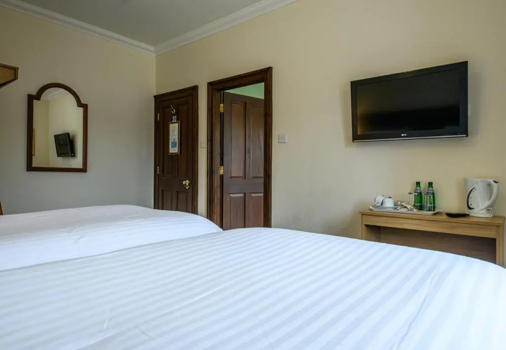a bedroom with a white bed and a flat screen tv at The Bridge Helmsdale in Helmsdale