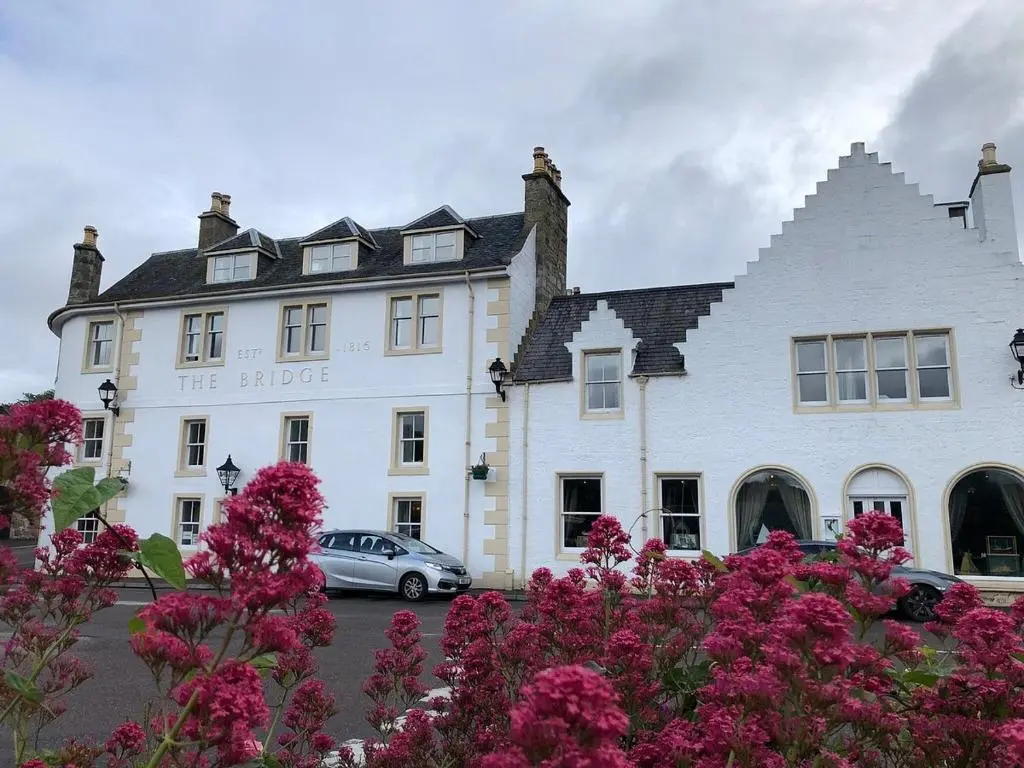 a white building with a car parked in front of it at The Bridge Helmsdale in Helmsdale