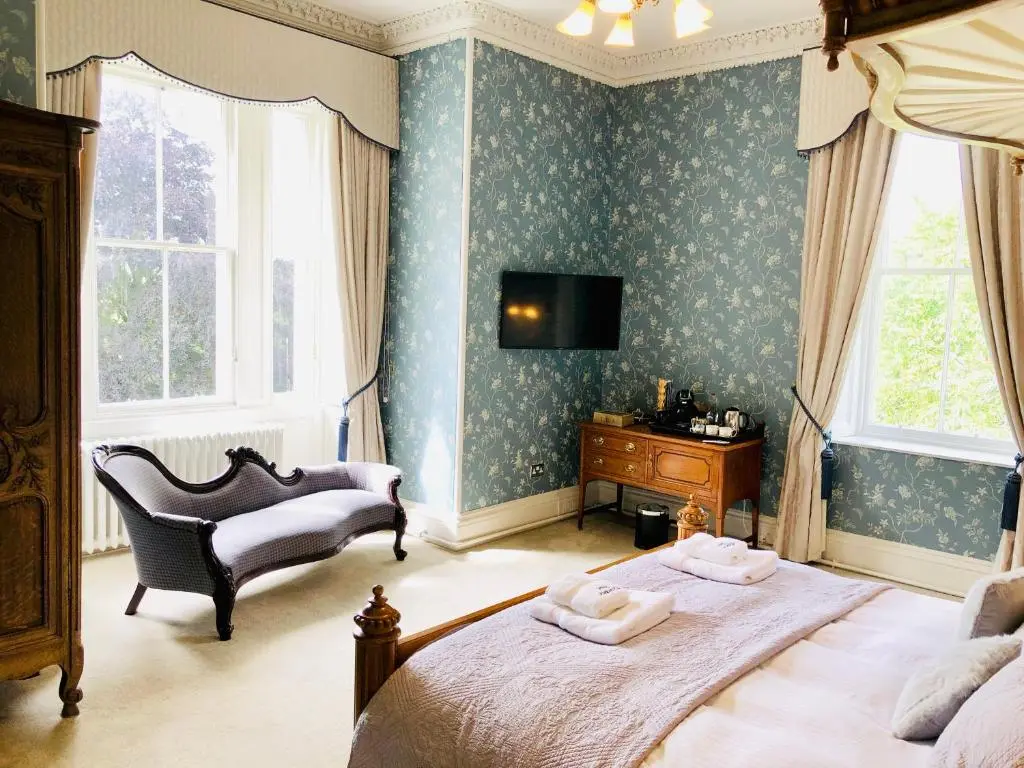 a bedroom with a bed and a chair and a television at Netherdale House & The Coach House in Turriff