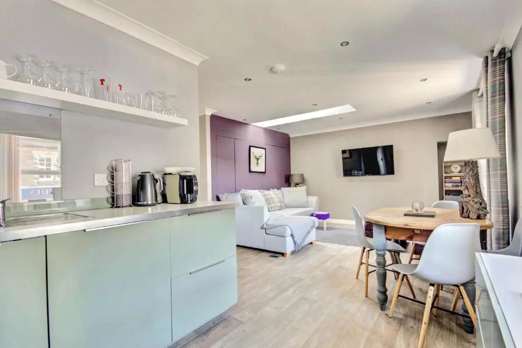 a kitchen and living room with a table and chairs at Thistle Apartment Golspie in Golspie