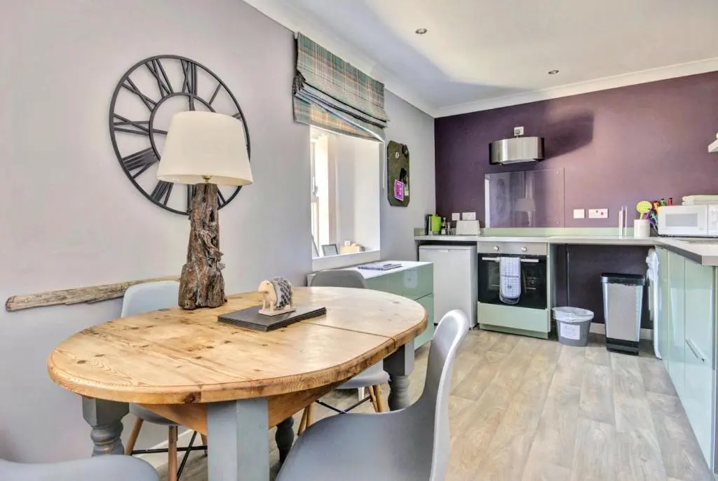 a kitchen with a wooden table and chairs and a dining room at Thistle Apartment Golspie in Golspie
