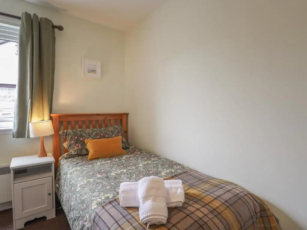 a bedroom with a bed with towels on it at Steam Cottage in Aviemore
