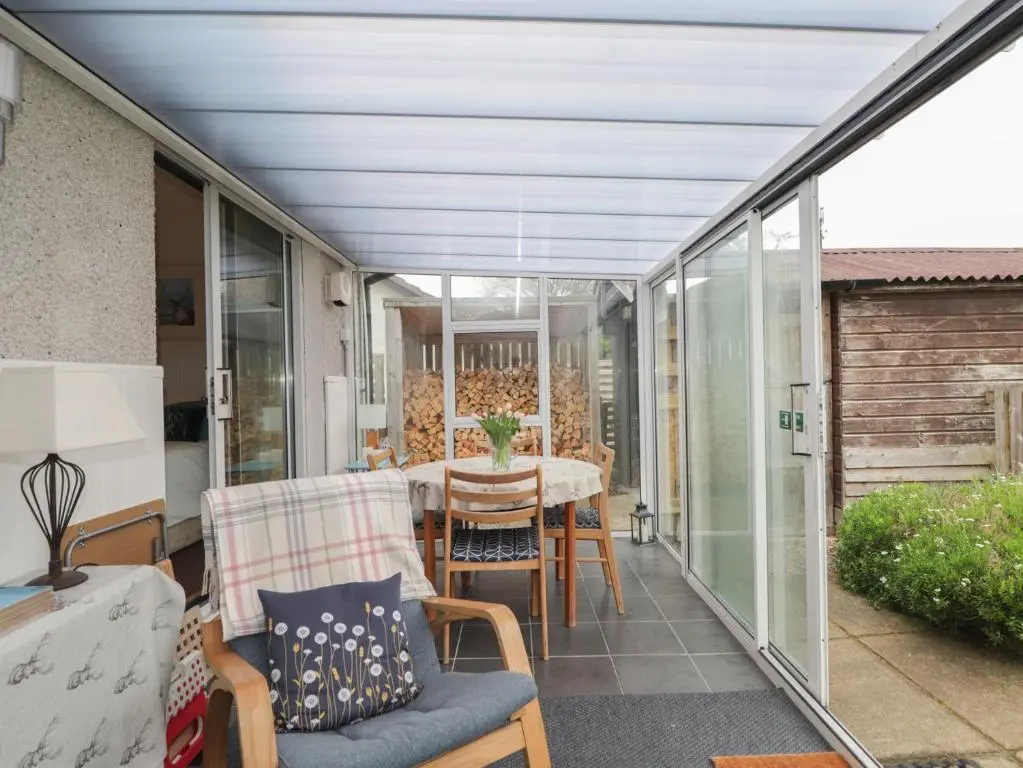 a screened in porch with a table and chairs at Steam Cottage in Aviemore