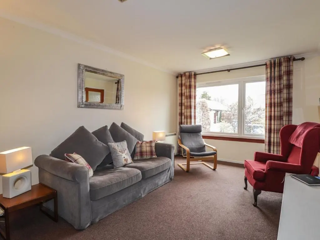 a living room with a couch and a chair at Steam Cottage in Aviemore