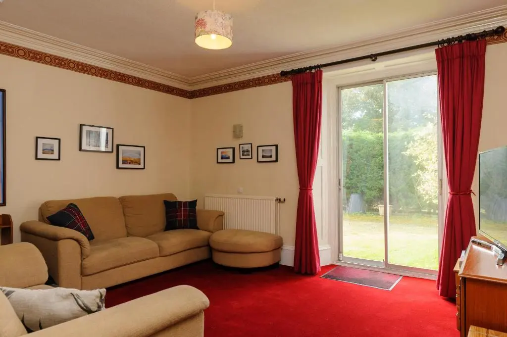 a living room with a couch and a large window at Alvey House in Newtonmore