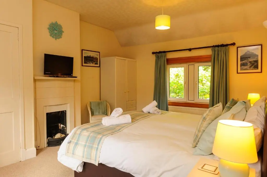 a bedroom with a bed with a fireplace and a tv at Alvey House in Newtonmore