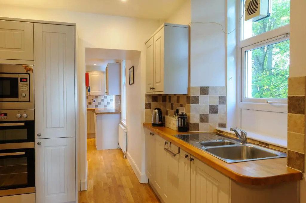 a kitchen with white cabinets and a sink and a window at Alvey House in Newtonmore