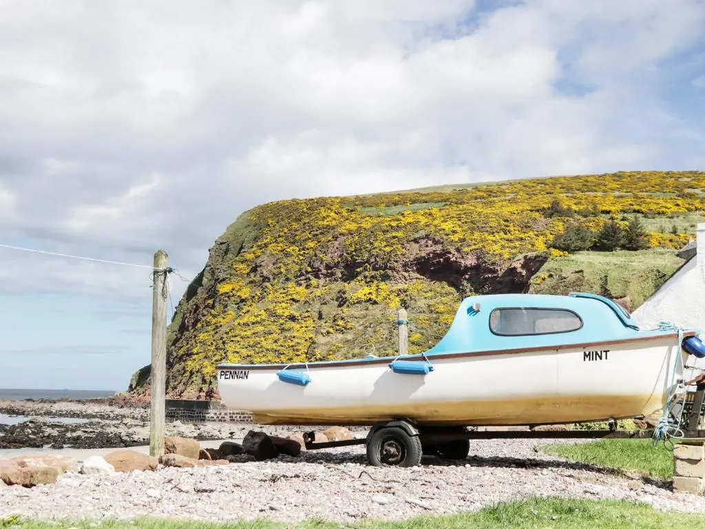 a boat sitting on the ground next to a hill at St Magnus Haven in Pennan