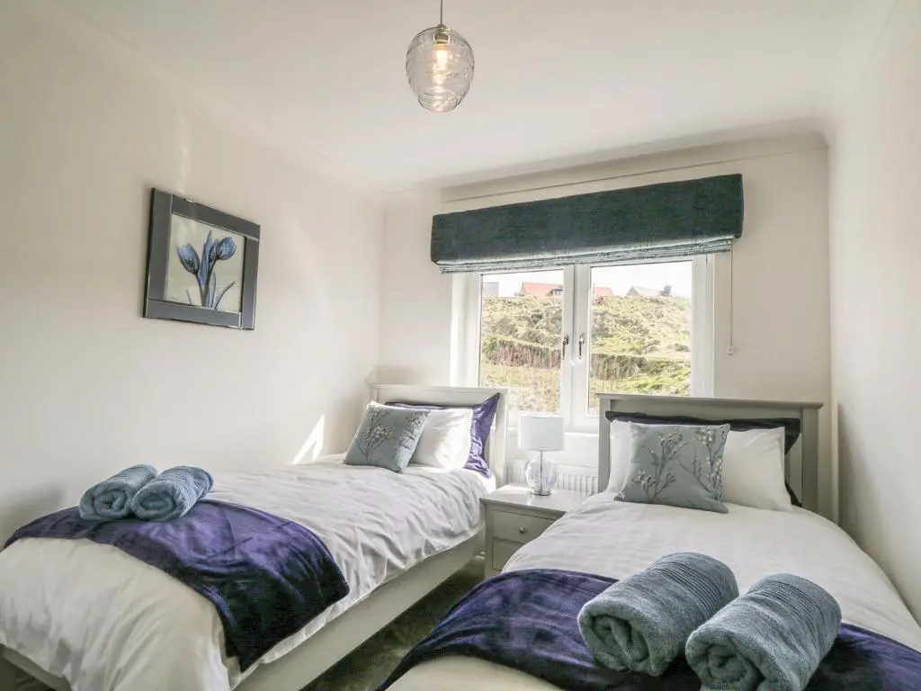two twin beds in a room with a window at 24 Waters Edge in Banff