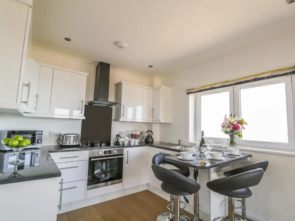 a kitchen with white cabinets and a table with chairs at 24 Waters Edge in Banff