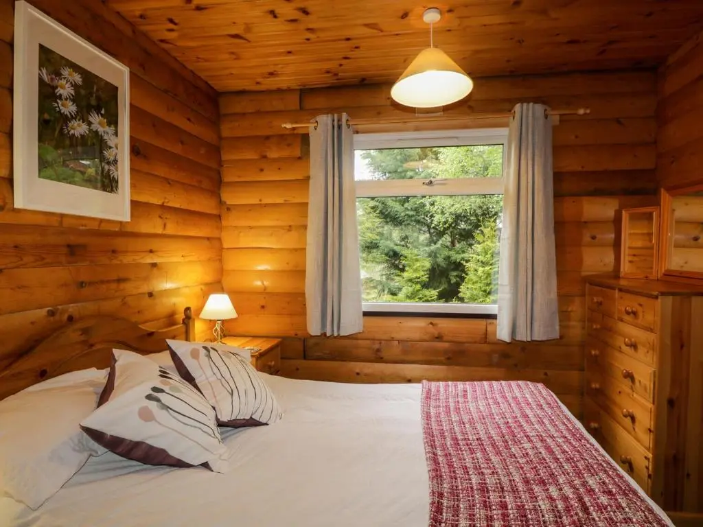 a bedroom with a bed in a log cabin at Eagle Lodge in Strathpeffer
