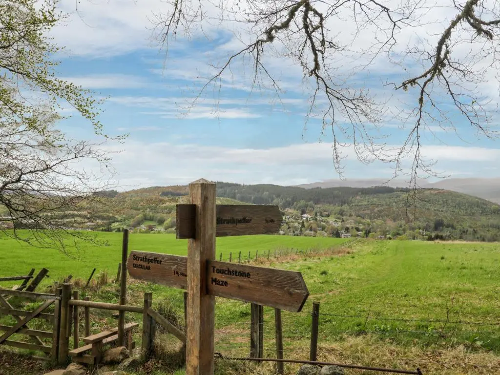 a wooden sign in the middle of a field at Eagle Lodge in Strathpeffer