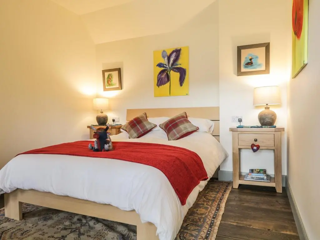a bedroom with a bed with a red blanket at East Craigdhu Cow Byre in Beauly