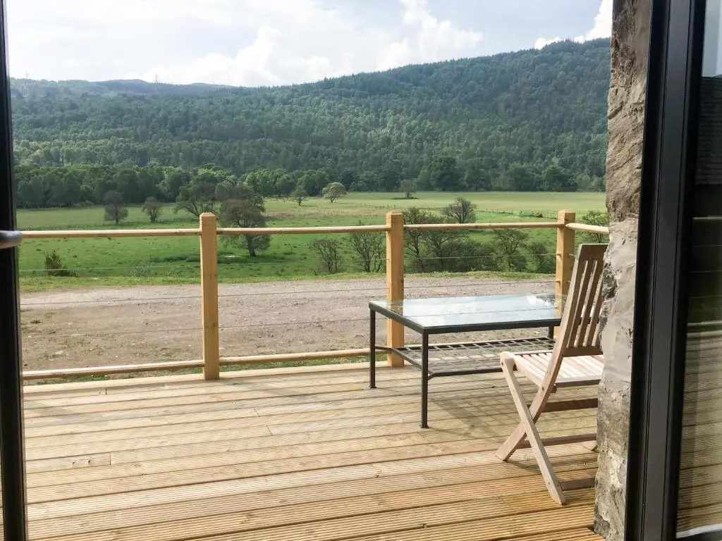 a wooden deck with a table and a bench on it at East Craigdhu Cow Byre in Beauly