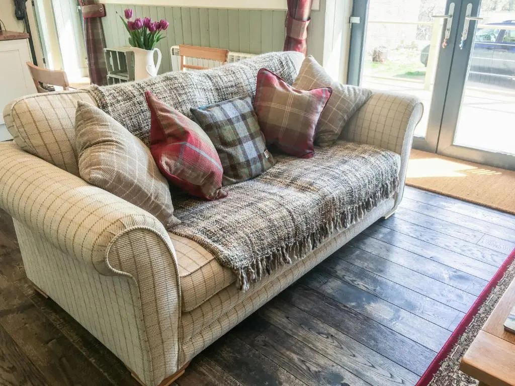 a couch with pillows on it in a living room at East Craigdhu Cow Byre in Beauly
