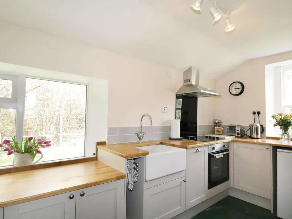 a kitchen with white cabinets and a sink and a window at Annfield in Aberlour