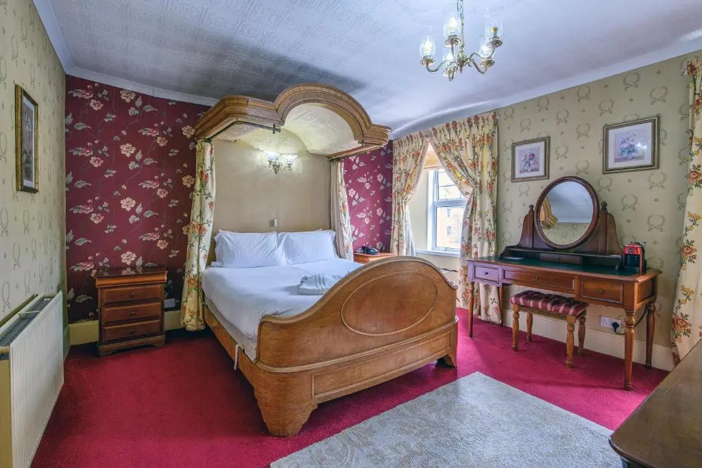 a bedroom with a large bed and a mirror at The Portland Hotel in Lybster