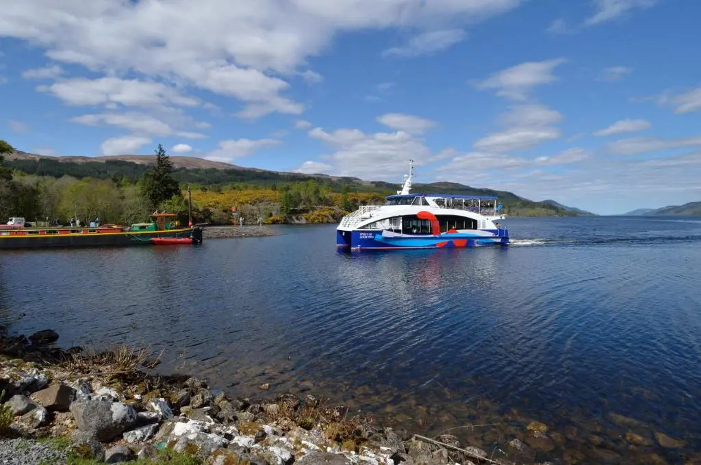 a large blue and white boat on a lake at The Bridge Suite in Invermoriston