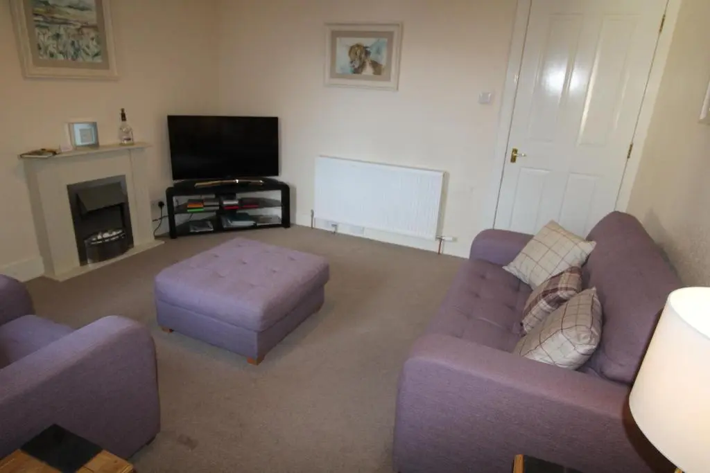 a living room with two purple couches and a tv at Easdale House Apartments in Inverness