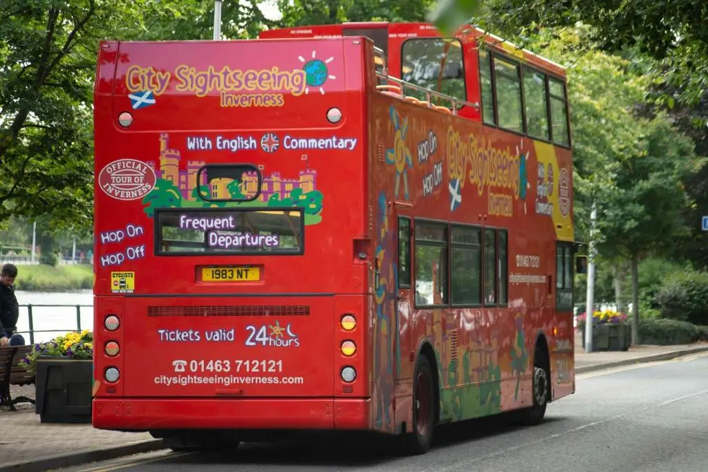 a red double decker bus driving down a street at Easdale House Apartments in Inverness